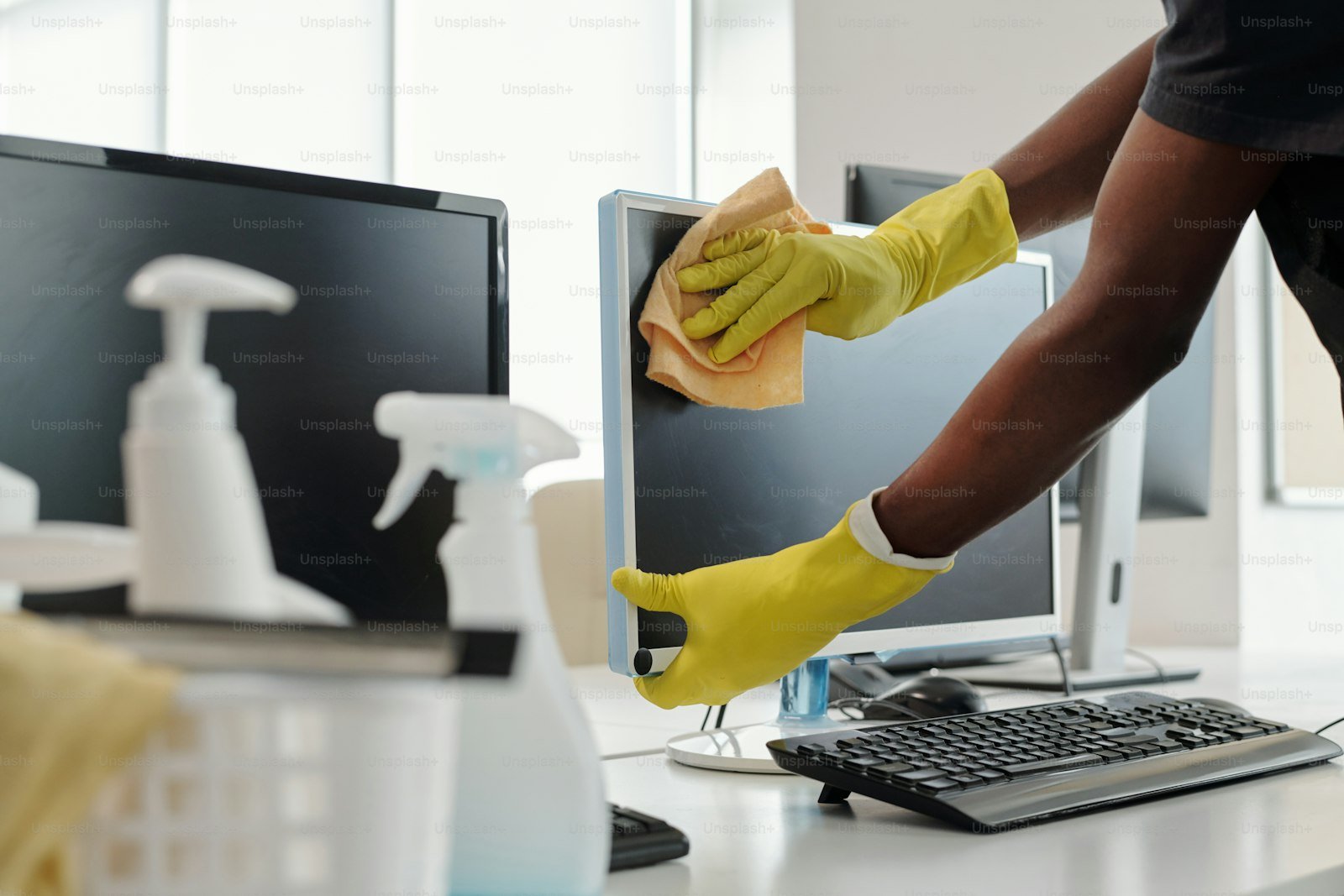 Gloved hand dusting office monitor